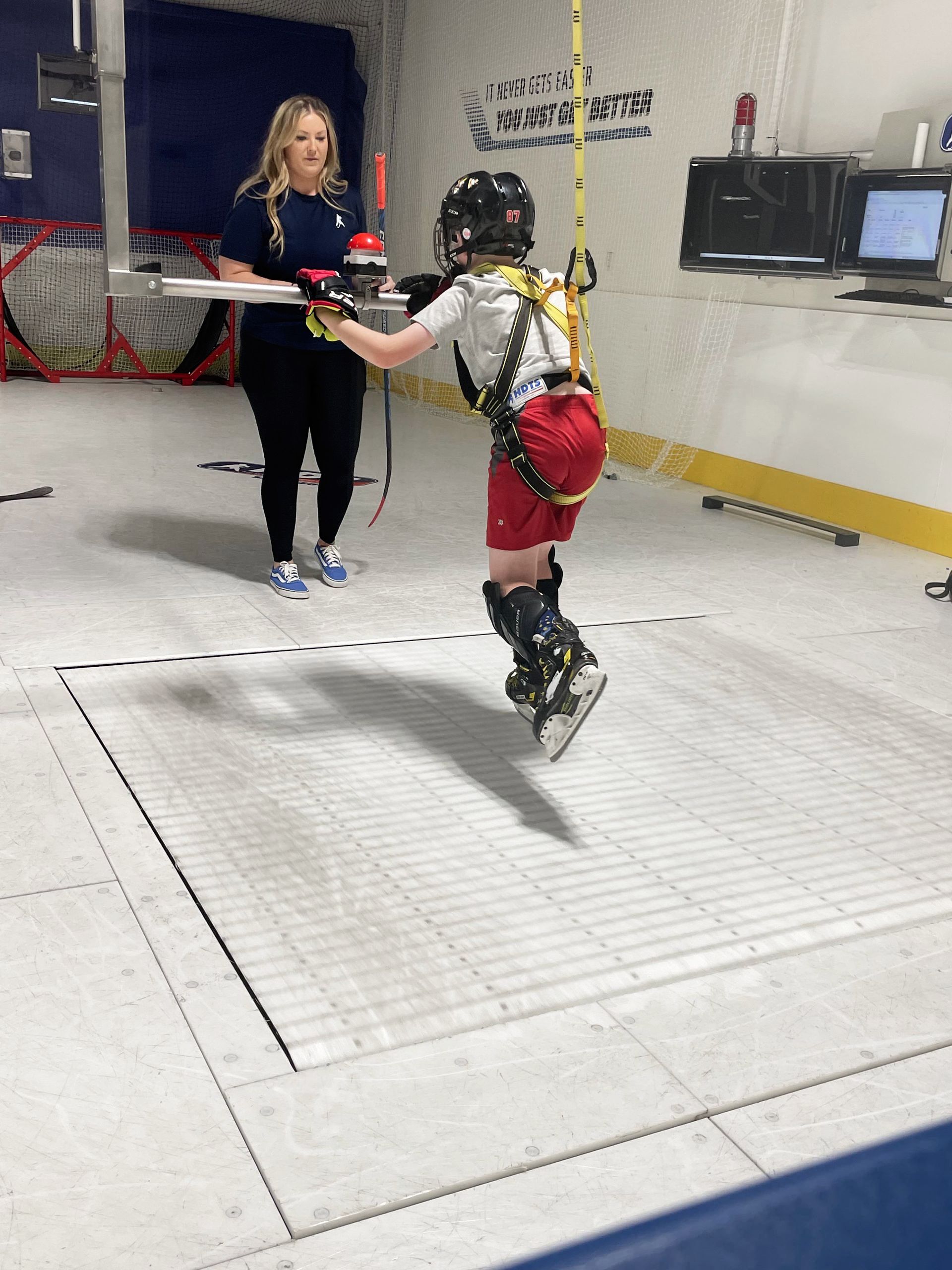 hockey player receiving instruction from coach on a skating treadmill