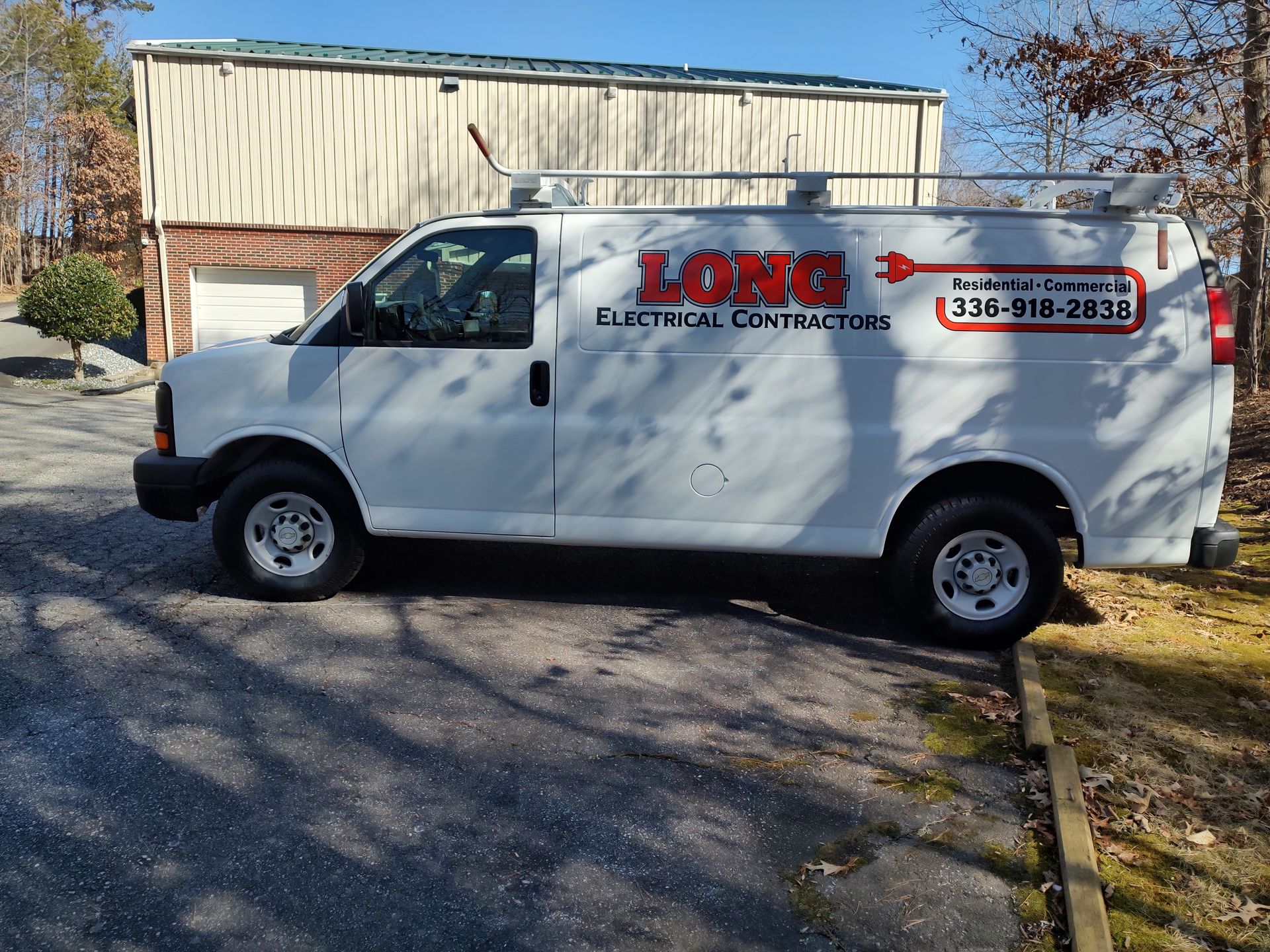 A long electrical contractors van is parked in front of a building