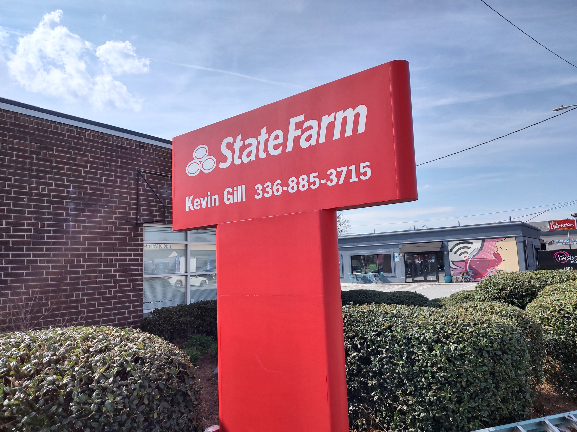 A red state farm sign in front of a brick building