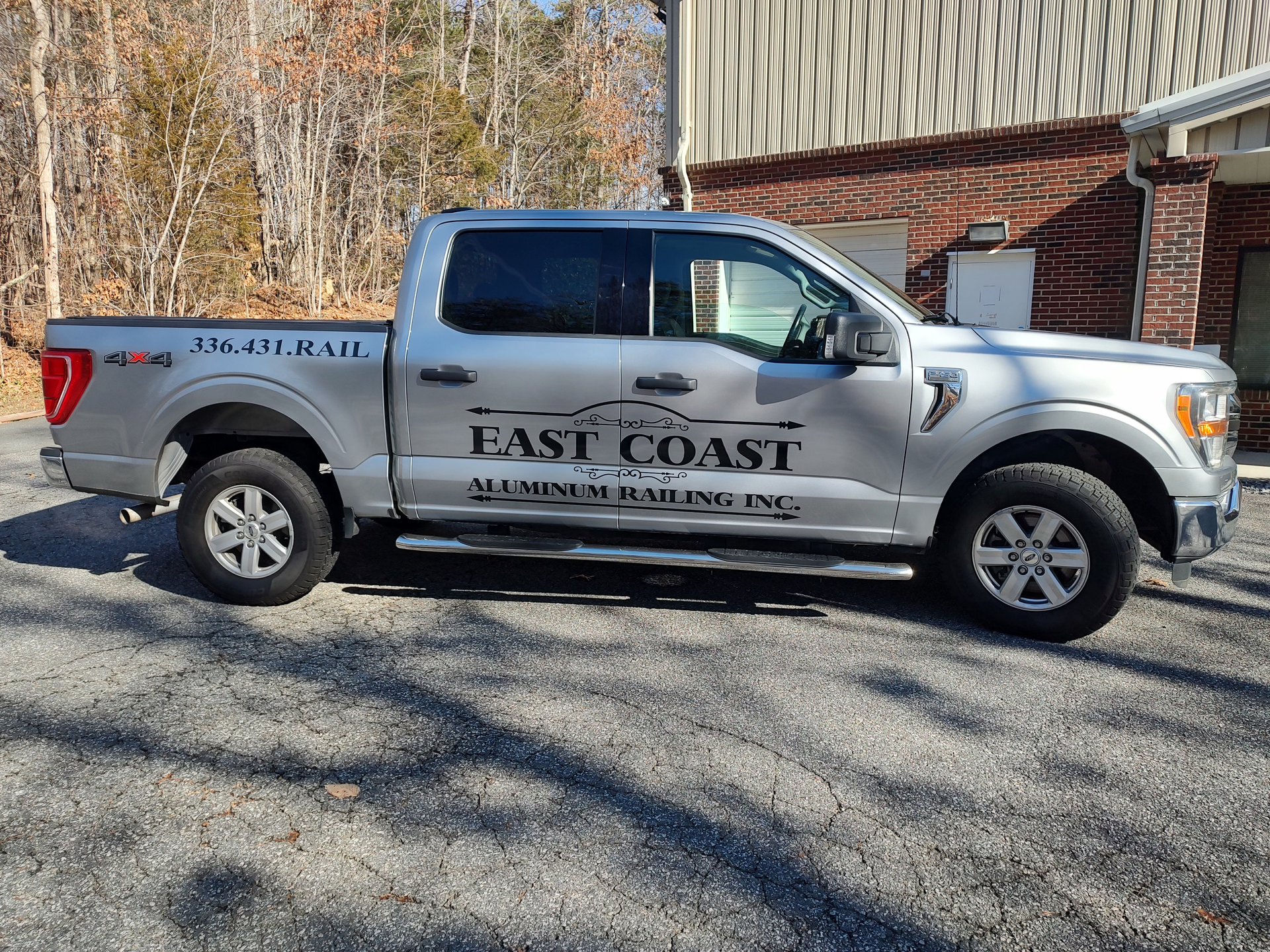 A white truck with the word east coast on the side is parked in front of a building.