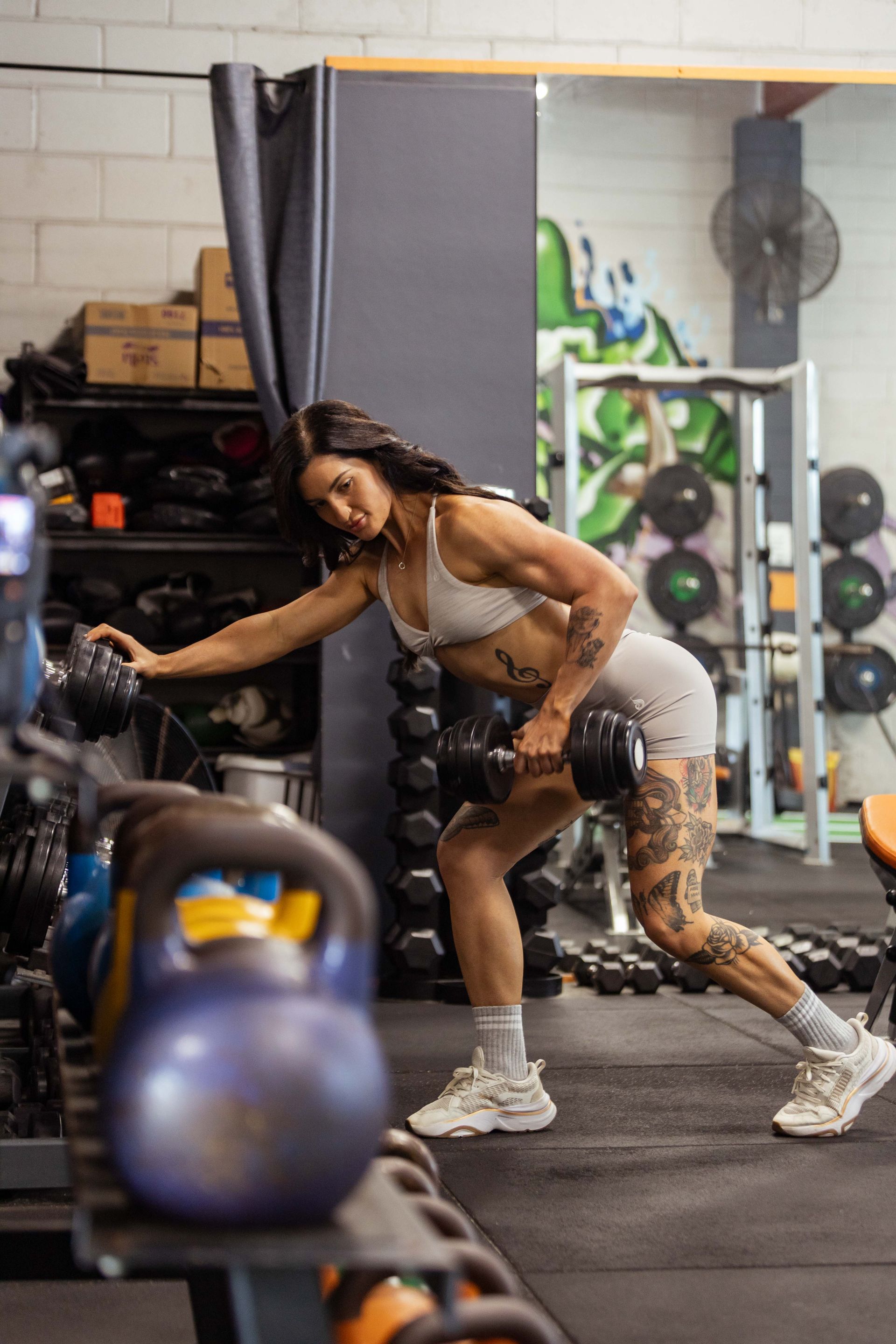 A woman is lifting a dumbbell in a gym. Madeline Klein - She Knows Fitness