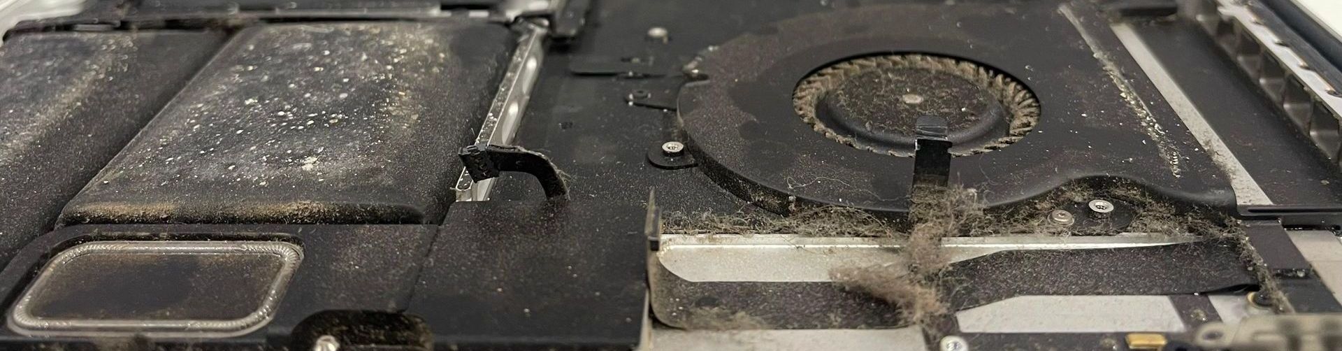 A dirty laptop computer is sitting on a table ready to be cleaned.