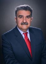 A man in a suit and tie is standing in front of a black background.