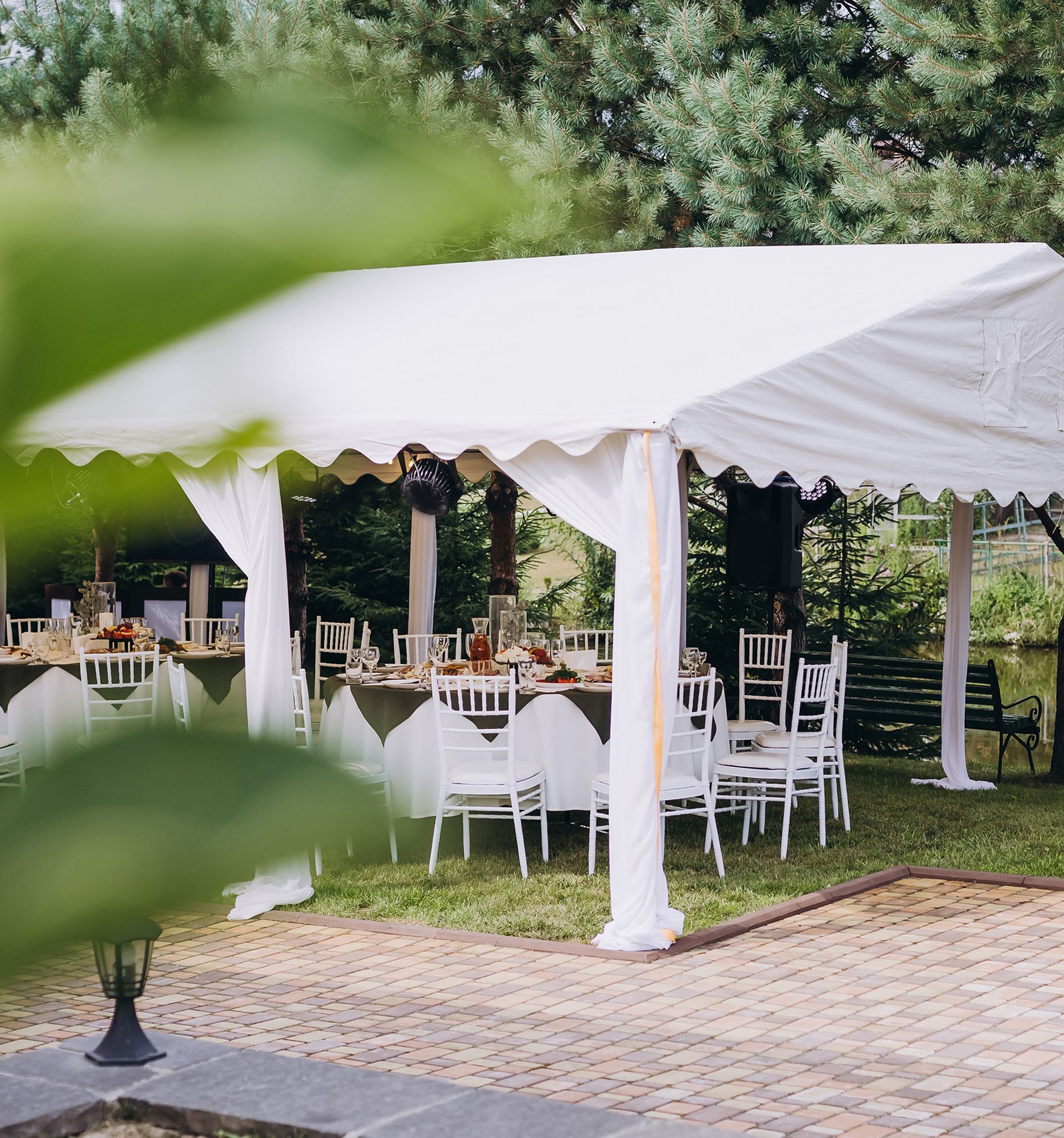A white tent with tables and chairs underneath it. A white tent with tables and chairs underneath it.