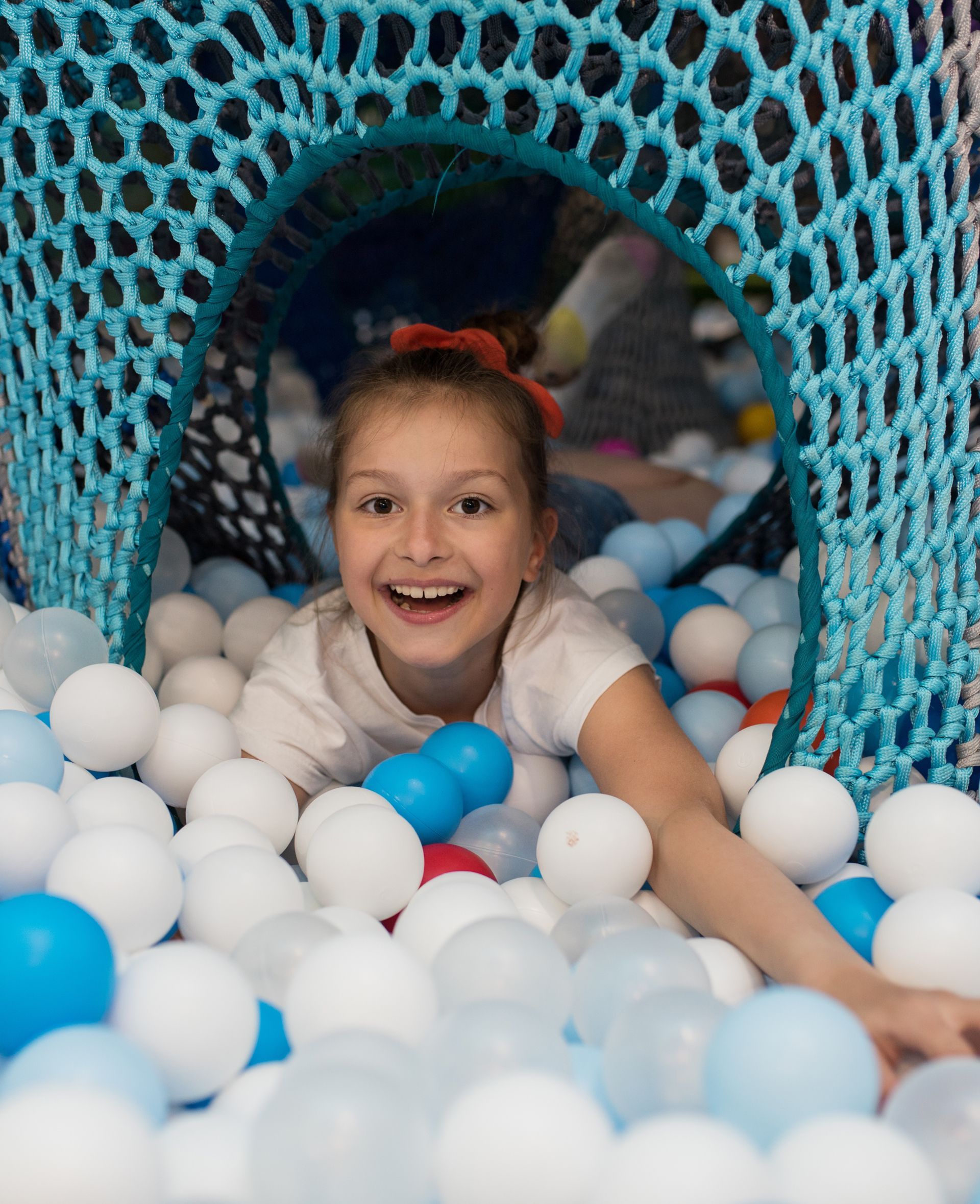 A little girl is playing in a ball pit. A little girl is playing in a ball pit.