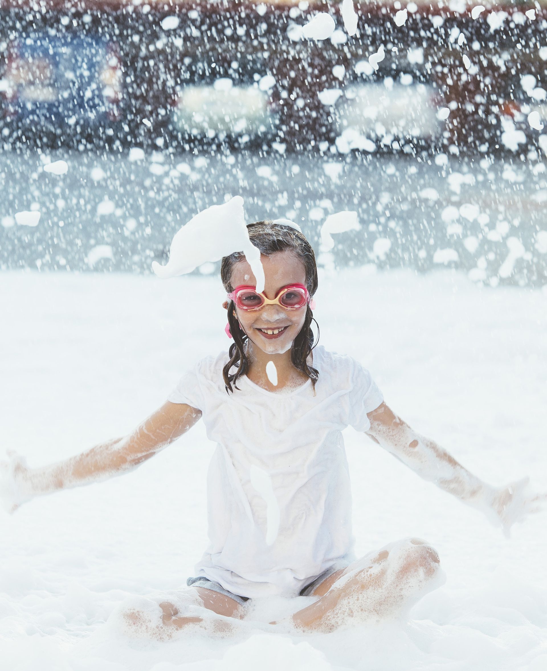 A little girl wearing sunglasses is sitting in a pool of foam. A little girl wearing sunglasses is sitting in a pool of foam.