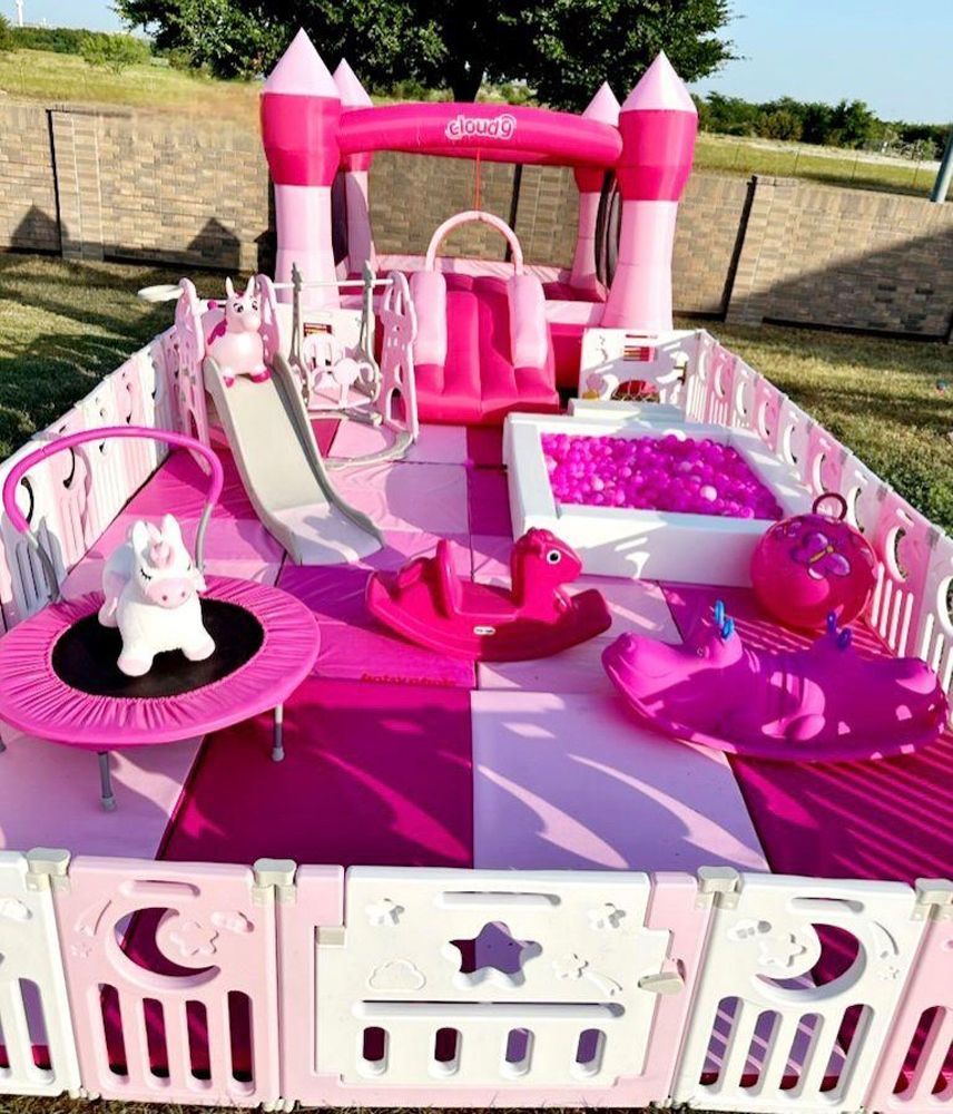 A pink bouncy house with a slide , trampoline , rocking horse , and unicorn.