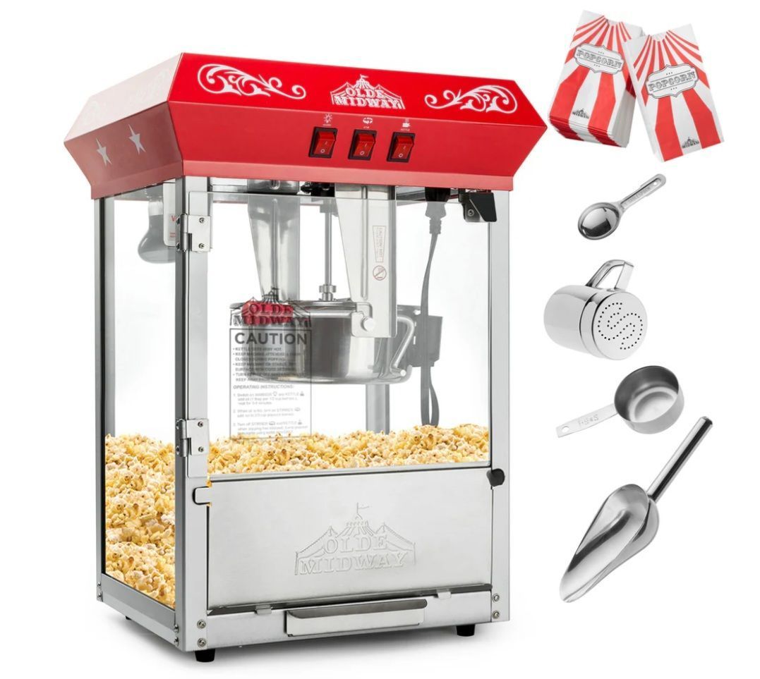 Two boxes of popcorn are sitting on a table next to a popcorn machine.