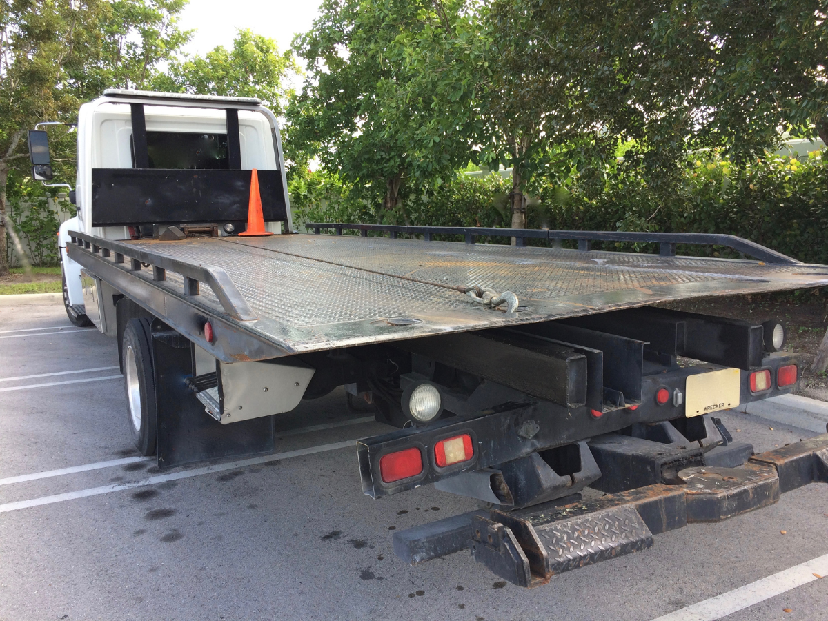 Tow truck with an empty flatbed parked outdoors, ready to load a vehicle.