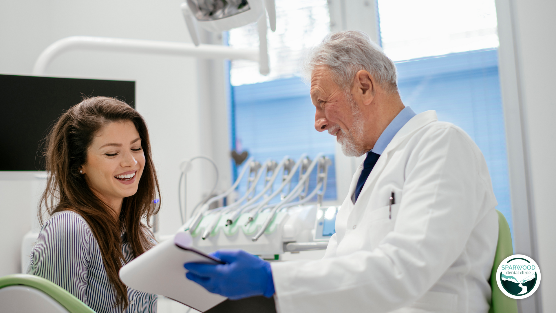 A dentist is talking to a patient in a dental office.