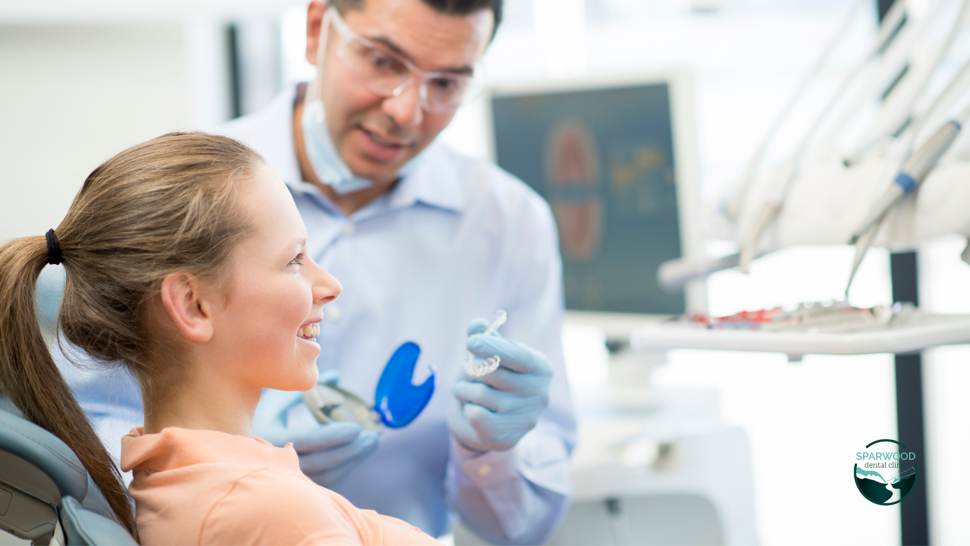 A woman is sitting in a dental chair while a dentist examines her teeth.