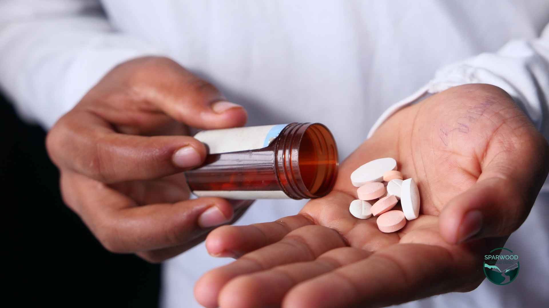 A person is pouring pills from a bottle into their hand.