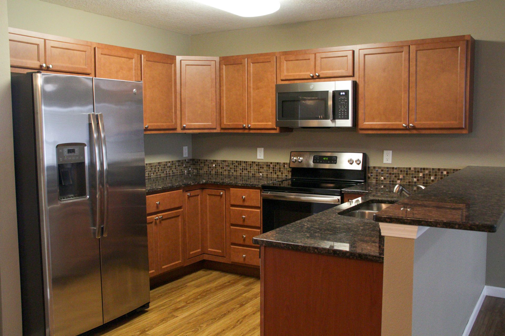 Kitchen with stainless steel appliances, brown cabinets, and granite countertops.