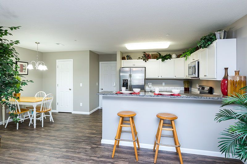 Open-concept kitchen/dining area with granite countertops, stainless steel appliances, and a small wooden dining table.