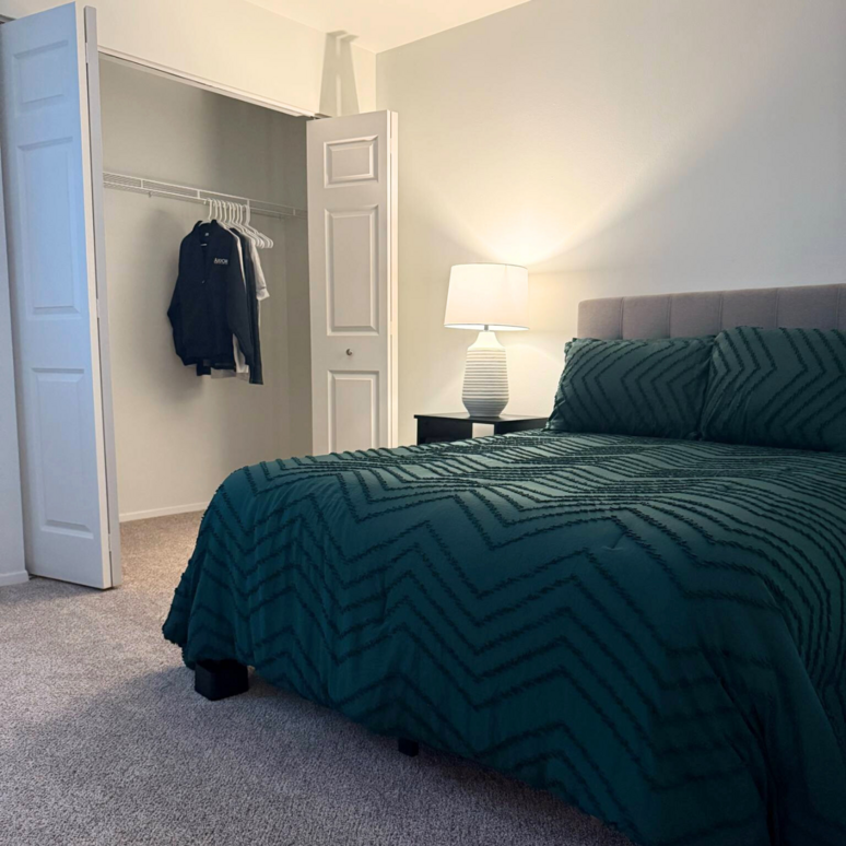 A bedroom with a large bed and a lamp