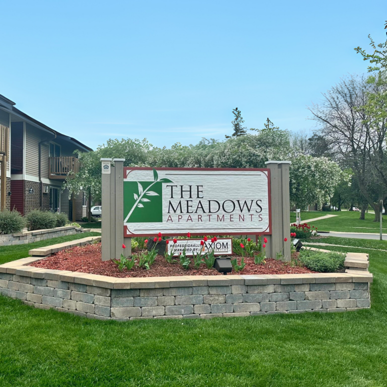 A sign for the meadows apartments is in front of a building