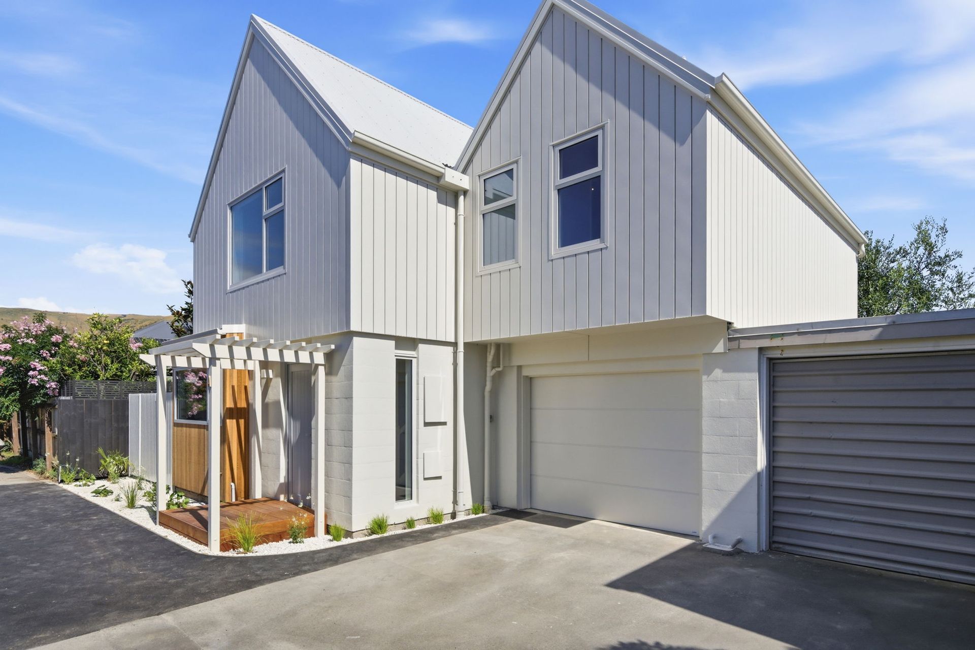 Modern two-story white house with gray roof, garage, and small front porch in a driveway