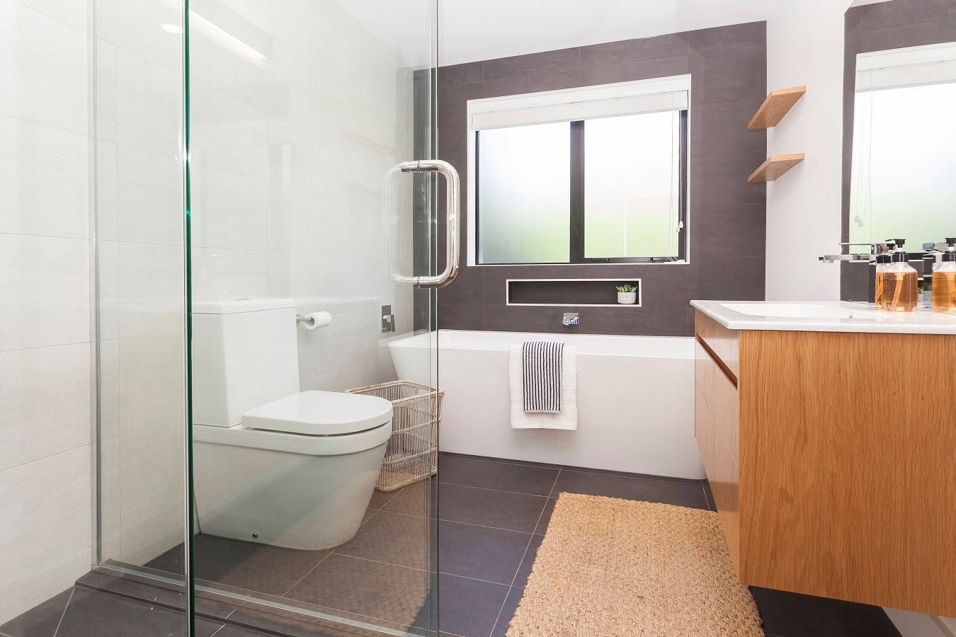Modern bathroom with glass shower, wall-mounted toilet, sink vanity, and large mirror