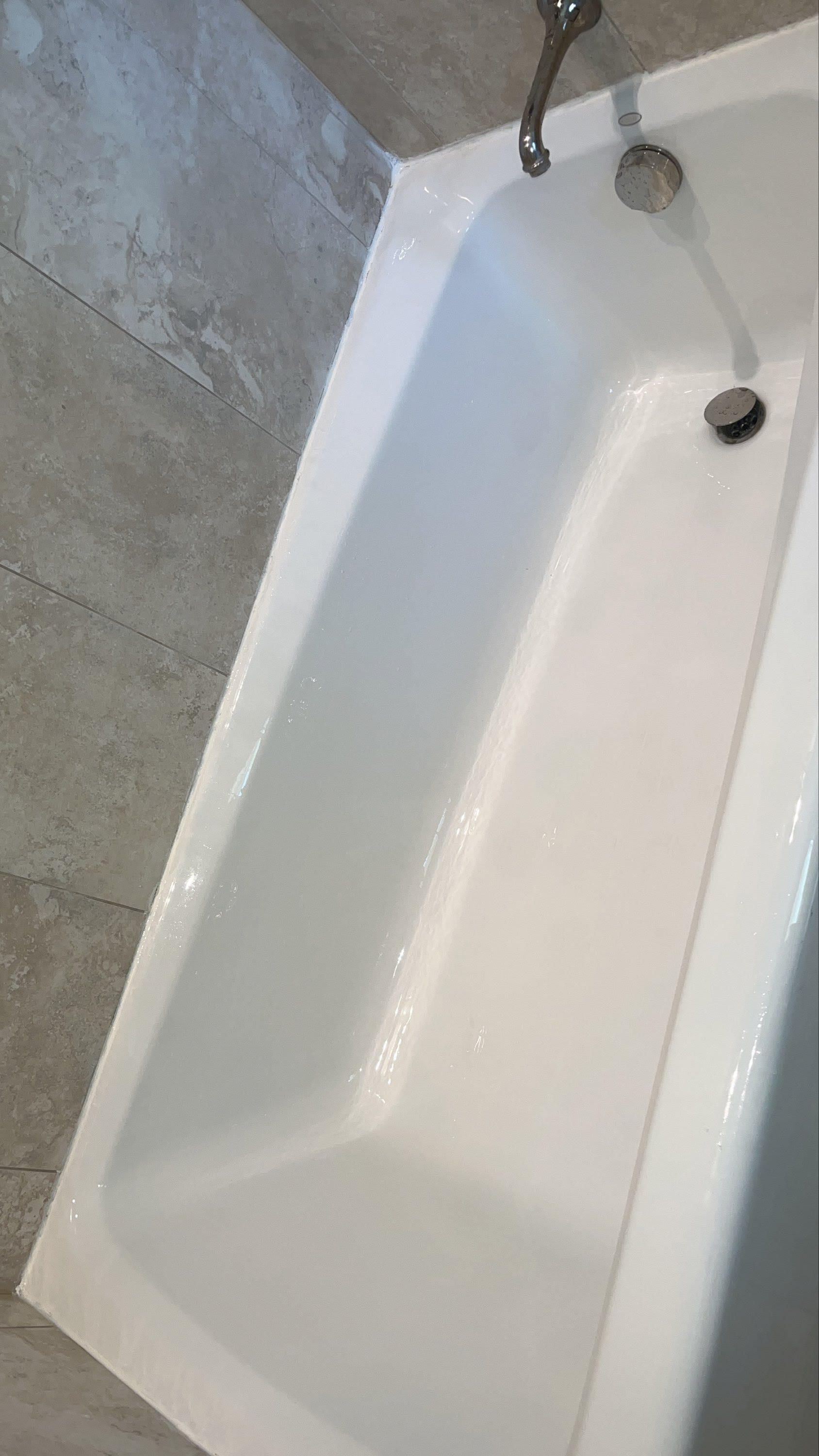 A white bathtub is sitting in a bathroom next to a tiled wall.
