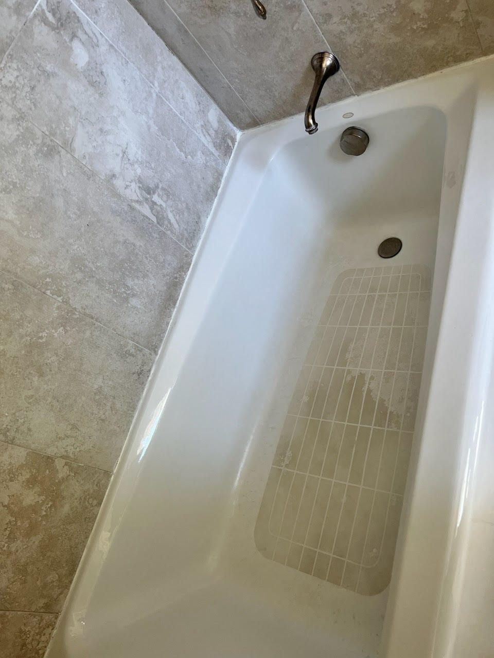 A white bathtub is sitting in a bathroom next to a tiled wall.