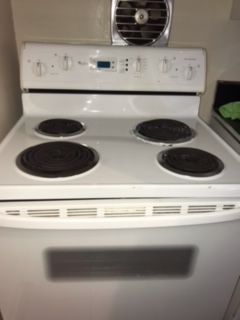 A white stove with four burners and a fan on top of it.