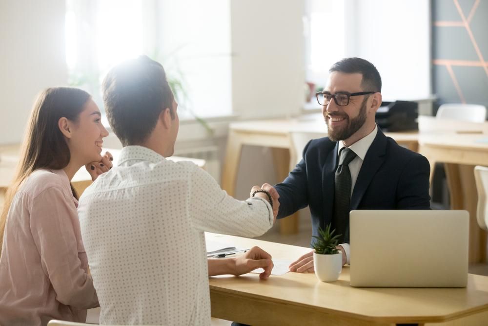 A Man and Woman Are Shaking Hands With a Man — All Finanz and Insurance Solutions PtyLtd in Airlie Beach, QLD