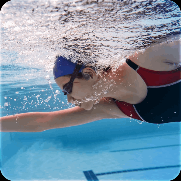 Swimmer in blue cap and red suit gliding underwater in a pool, arm stretched forward.