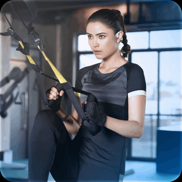 Woman exercising with suspension straps in a gym, wearing black workout clothes.