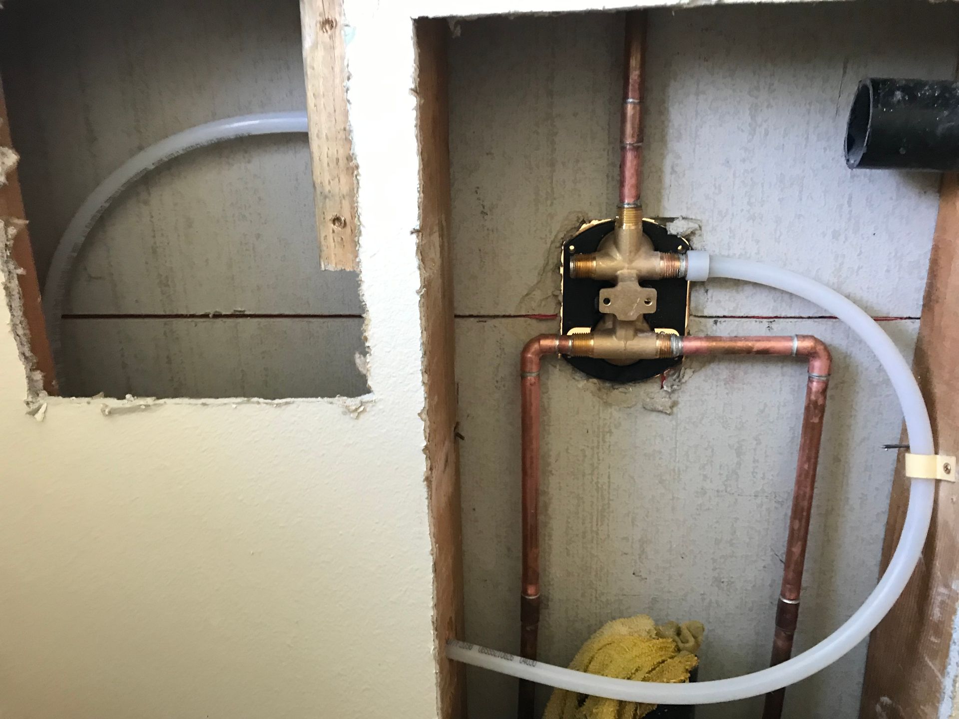 A bathroom with copper pipes coming out of a hole in the wall.