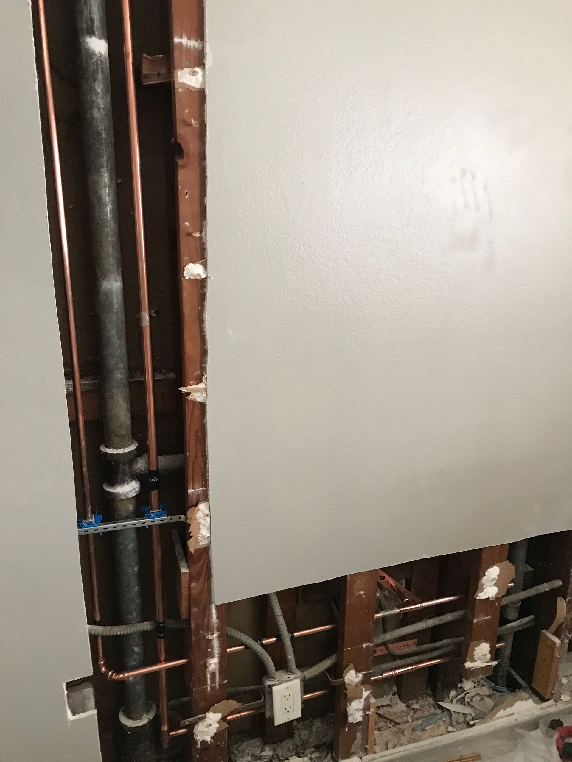 A hole in a wall with copper pipes coming out of it