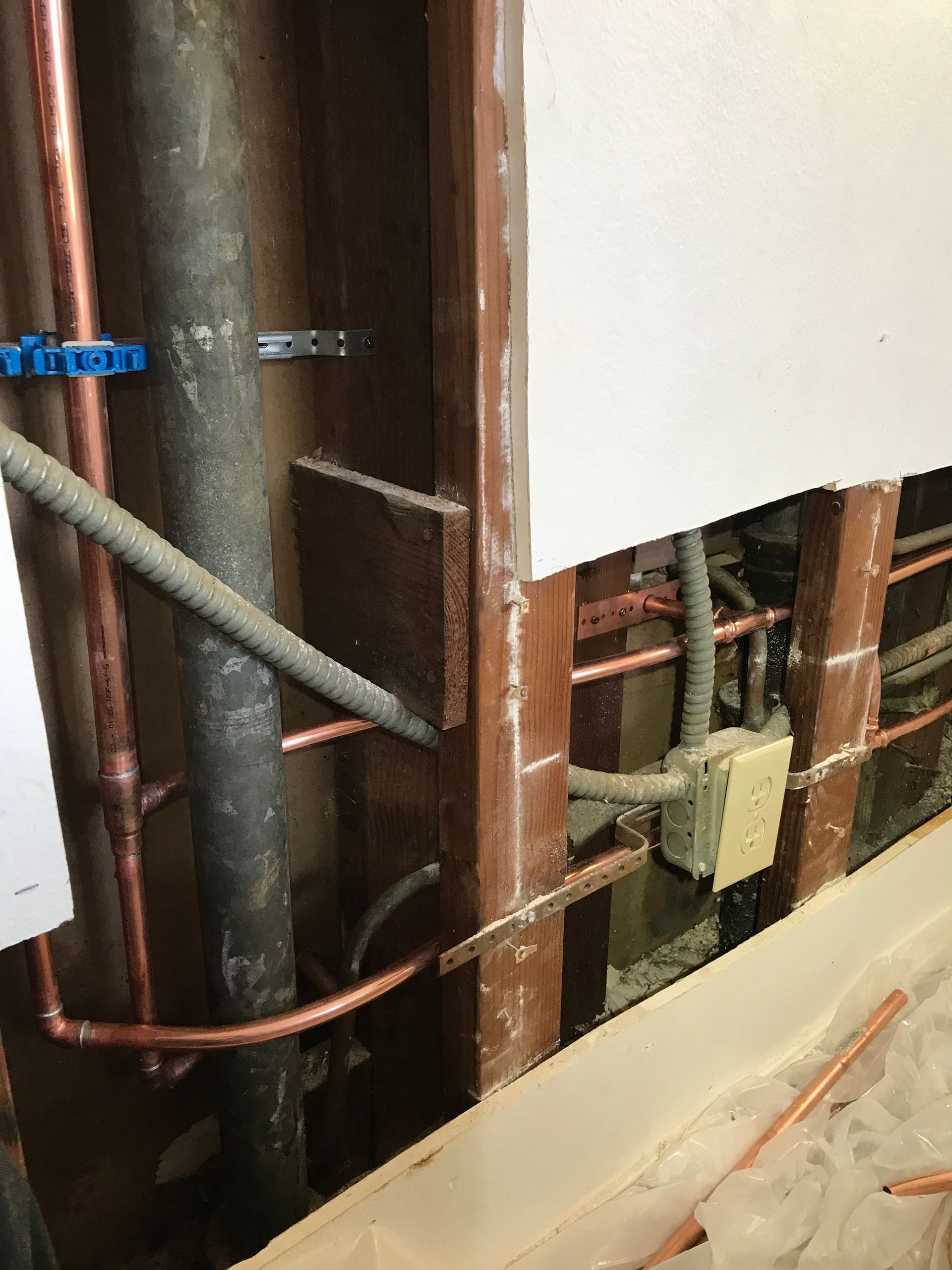 A wall with copper pipes and wires coming out of it