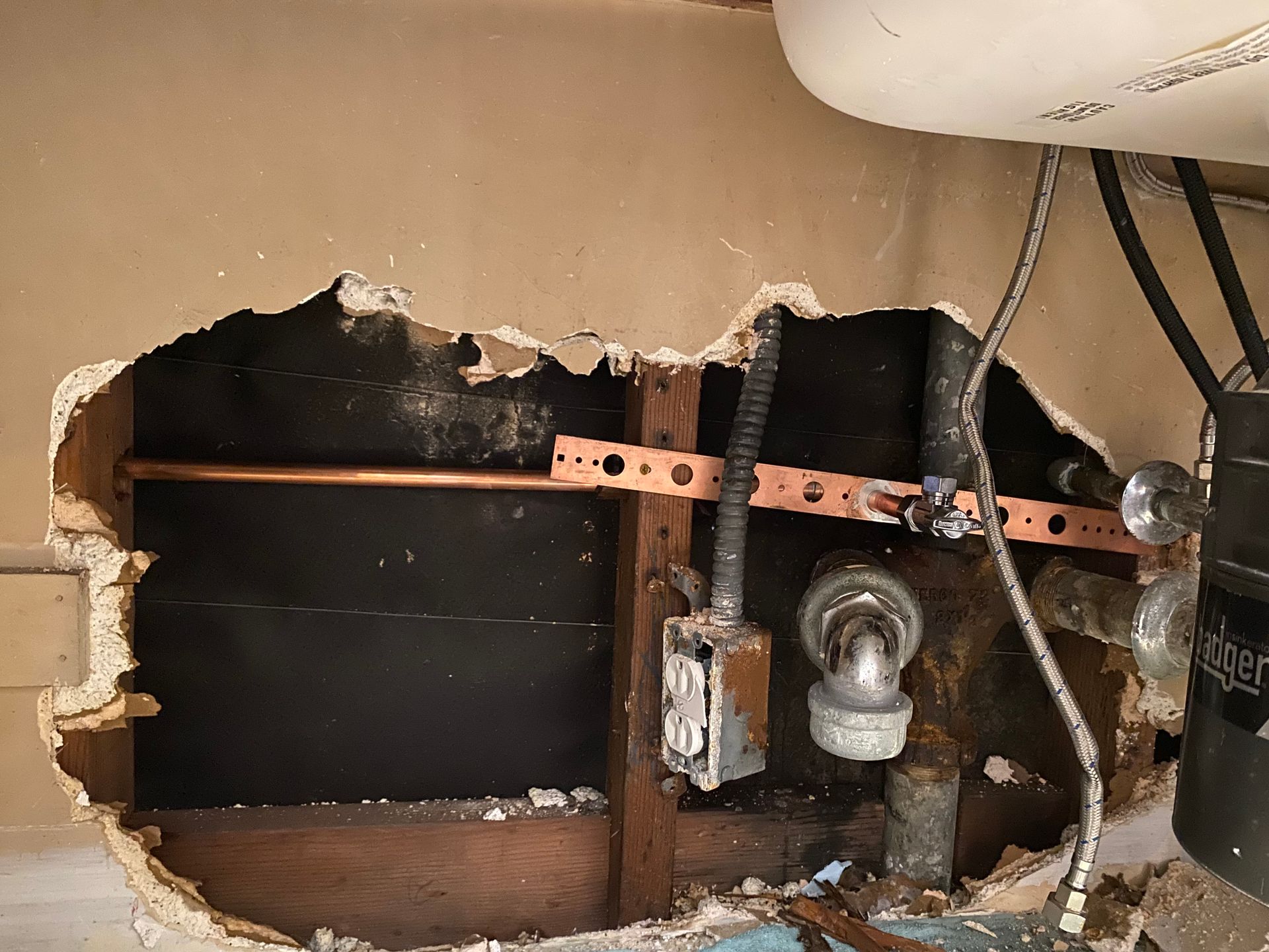 A hole in a wall with copper pipes coming out of it