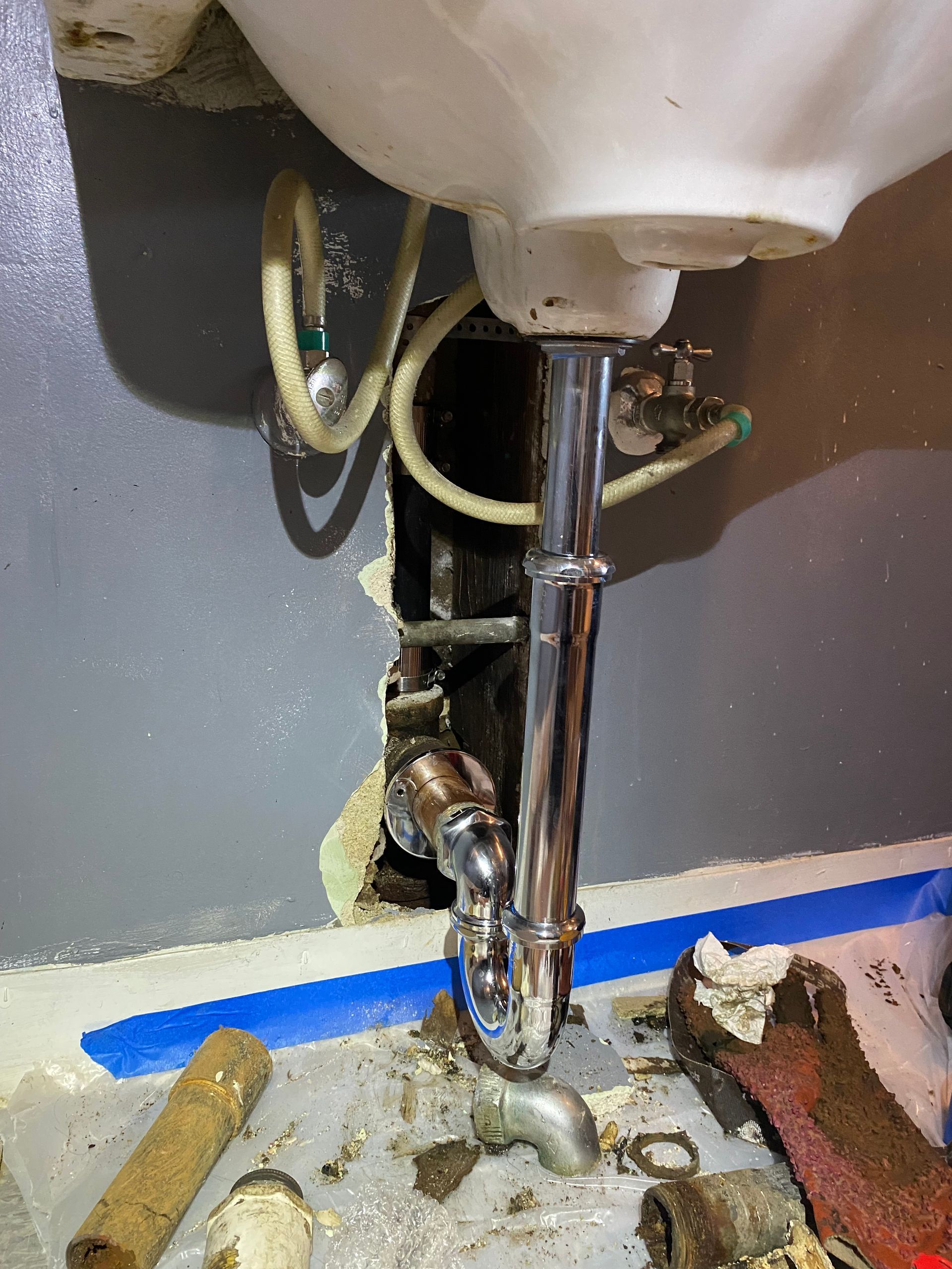 A bathroom sink with a hole in the wall and a pipe coming out of it.