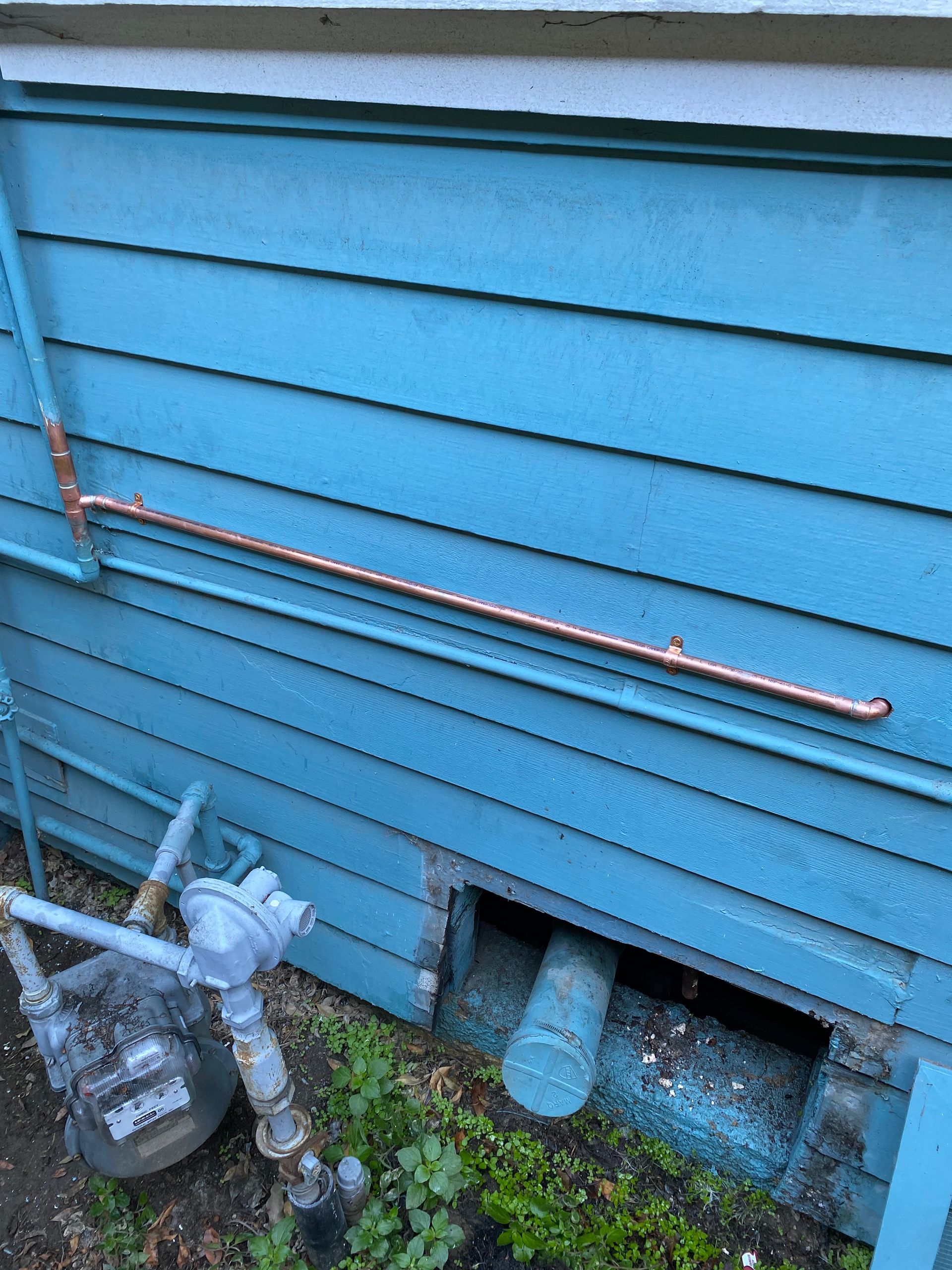 A blue house with copper pipes on the side of it