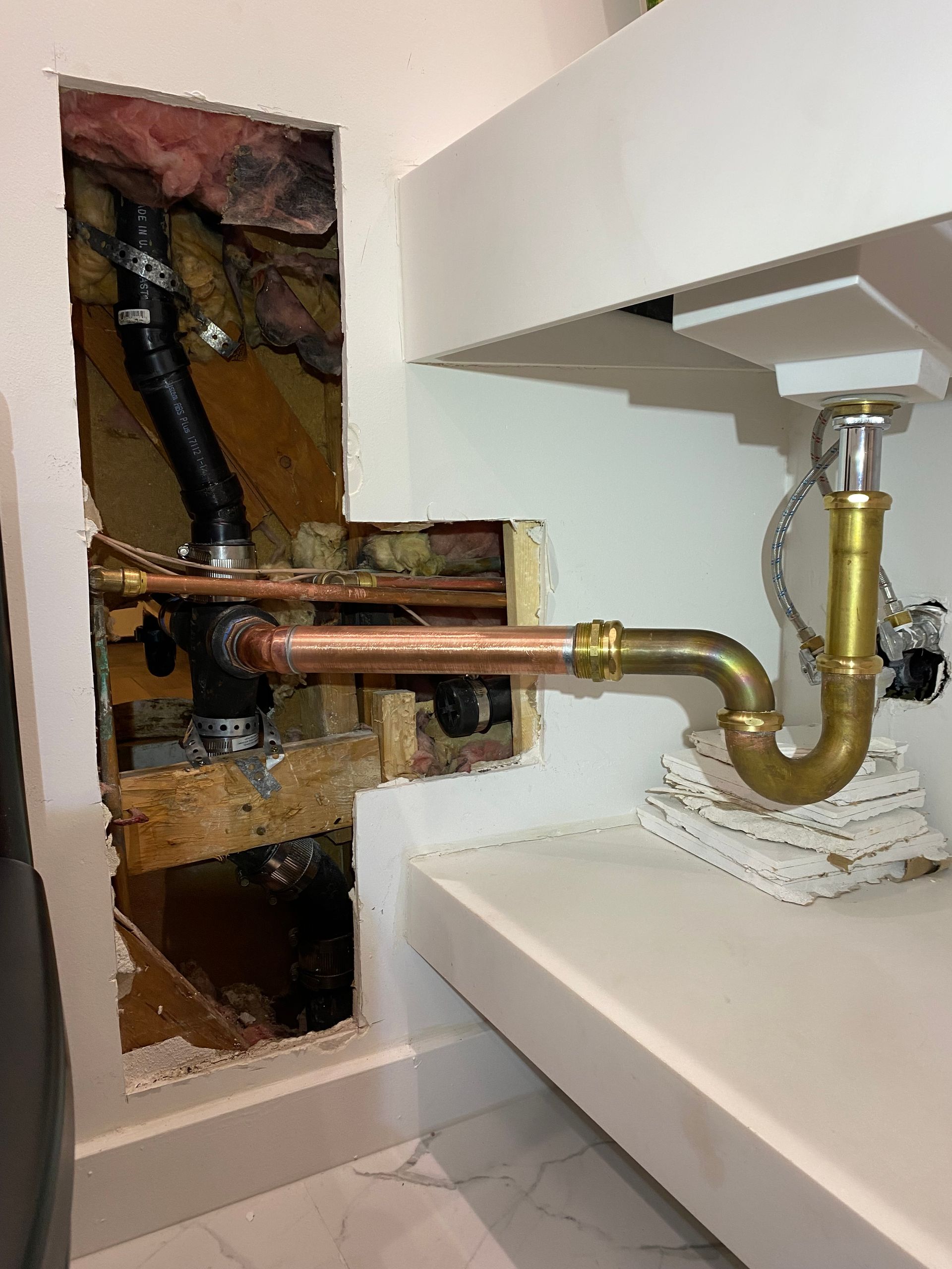 A bathroom sink with a copper pipe coming out of it.