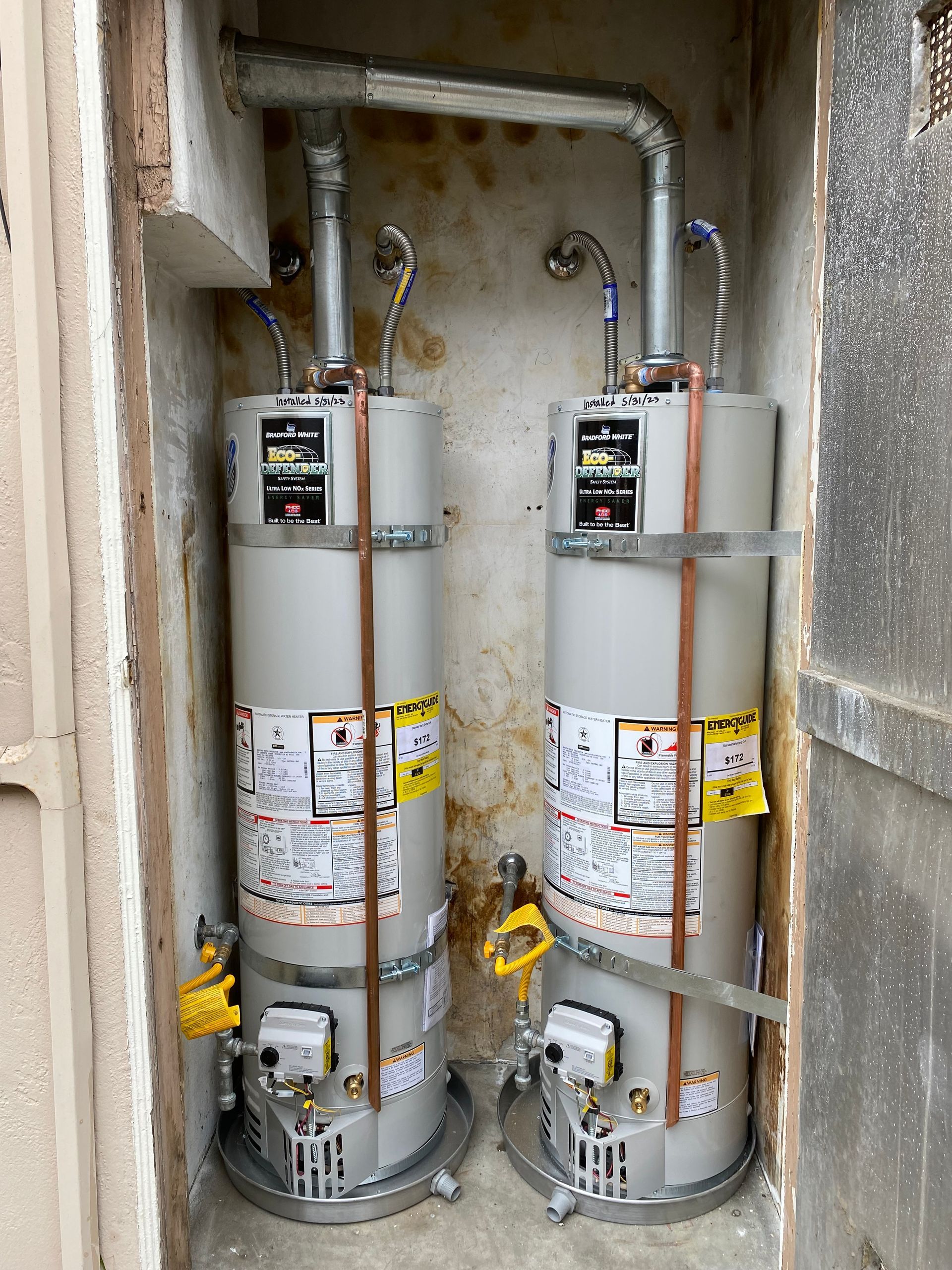 Two water heaters are sitting next to each other in a room.
