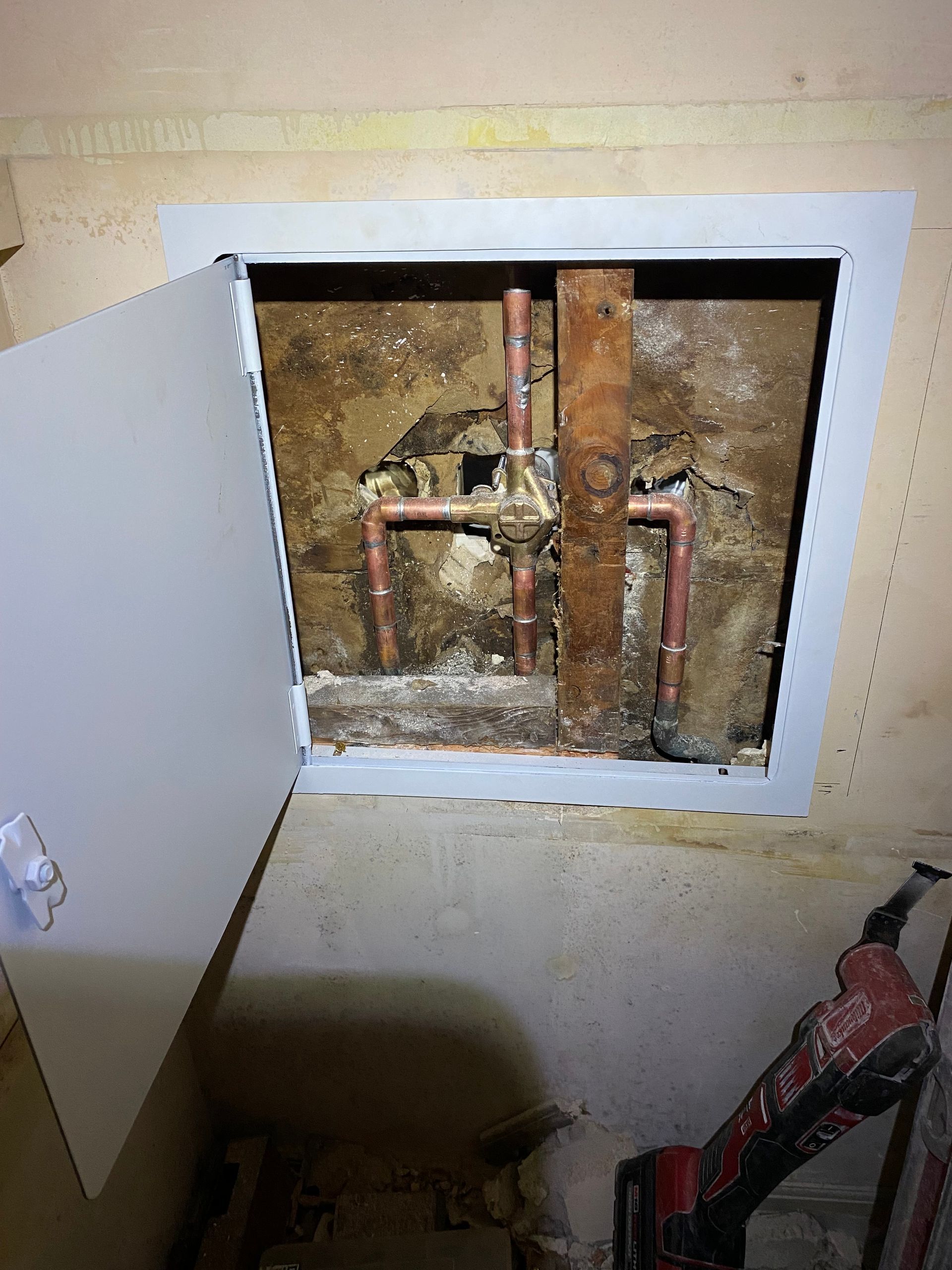 A hole in the wall with pipes coming out of it.