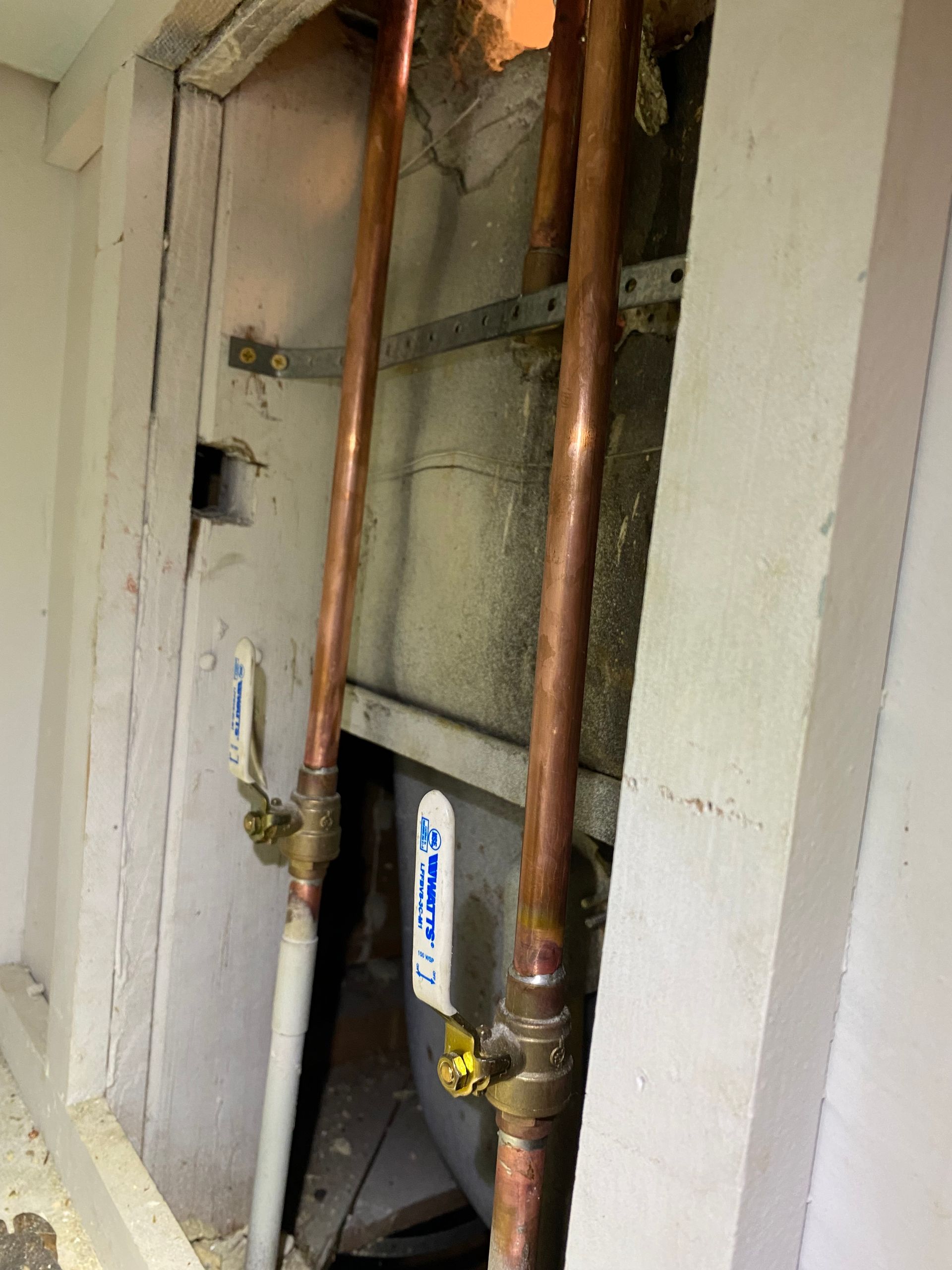A copper pipe is hanging from a wall in a room.
