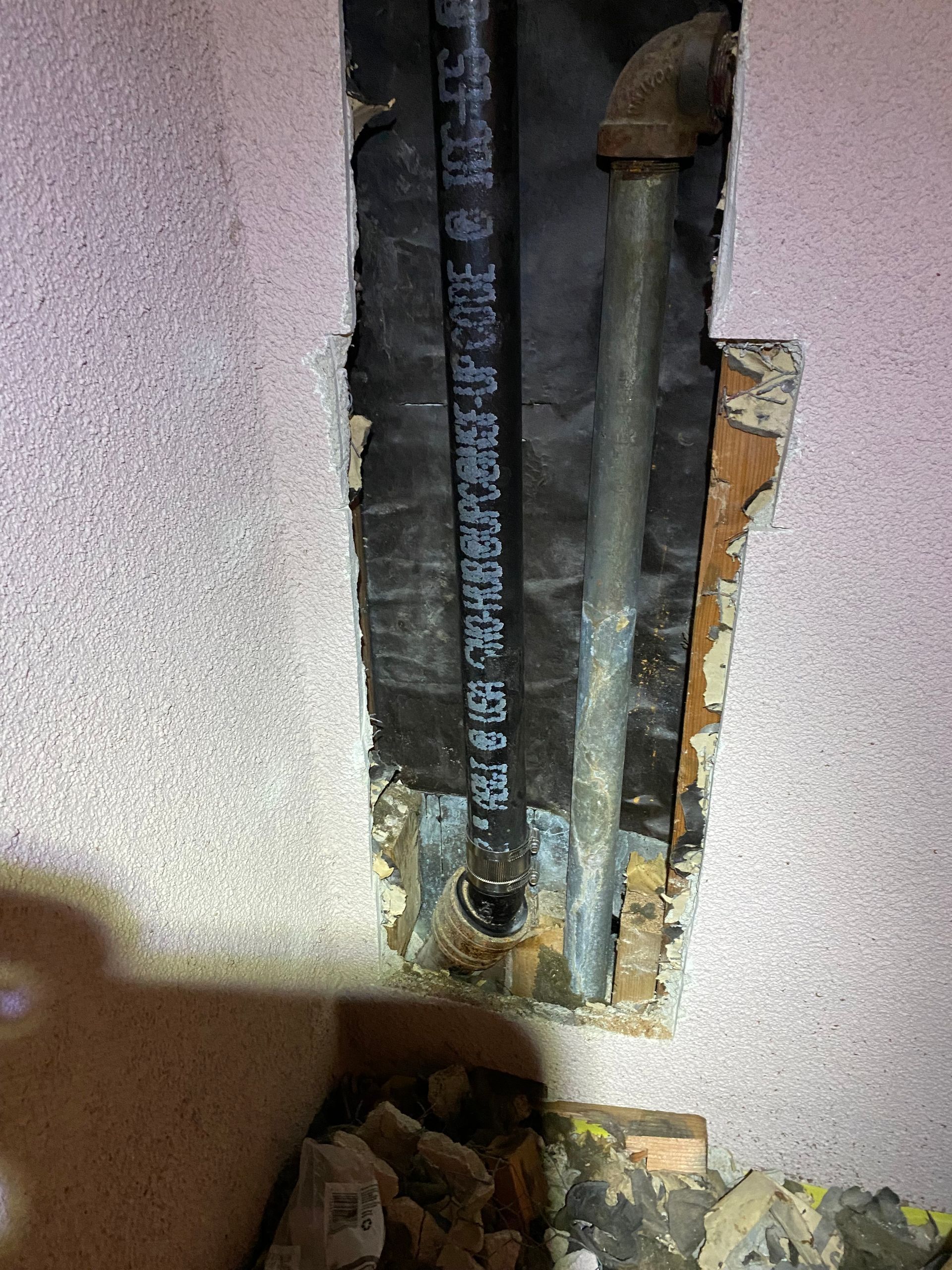 A pipe is coming out of a hole in a wall.