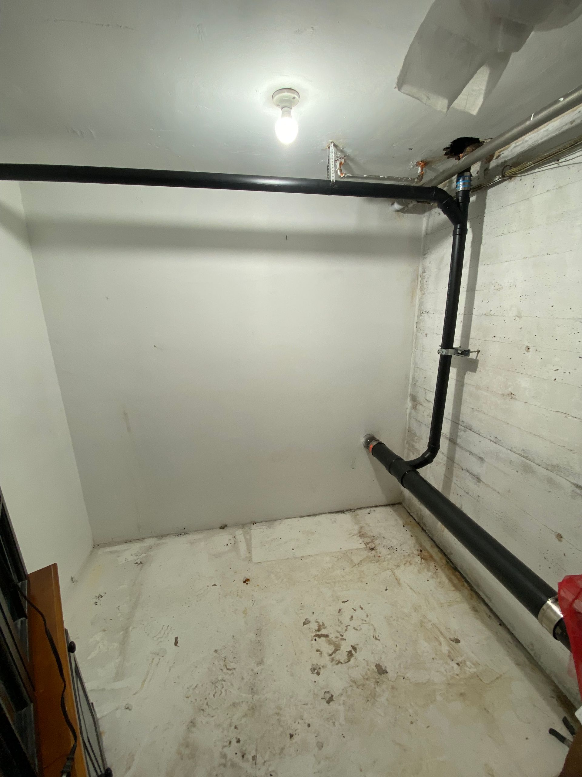 A room with a lot of pipes coming out of it and a light on the ceiling.