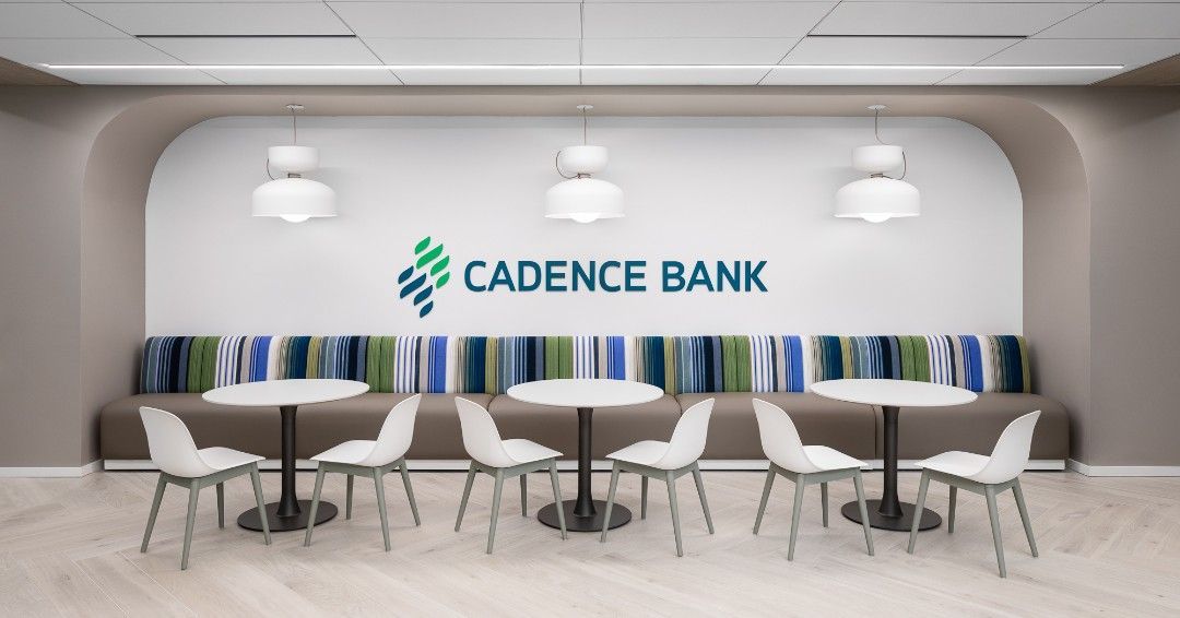 Cadence Bank lobby with white tables, chairs, and logo, cushioned seating, and pendant lights.