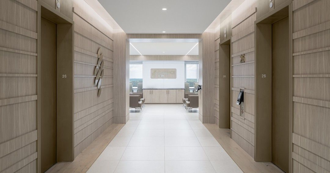 Hallway with three elevators, light wood paneling, and a bright, minimalist design.