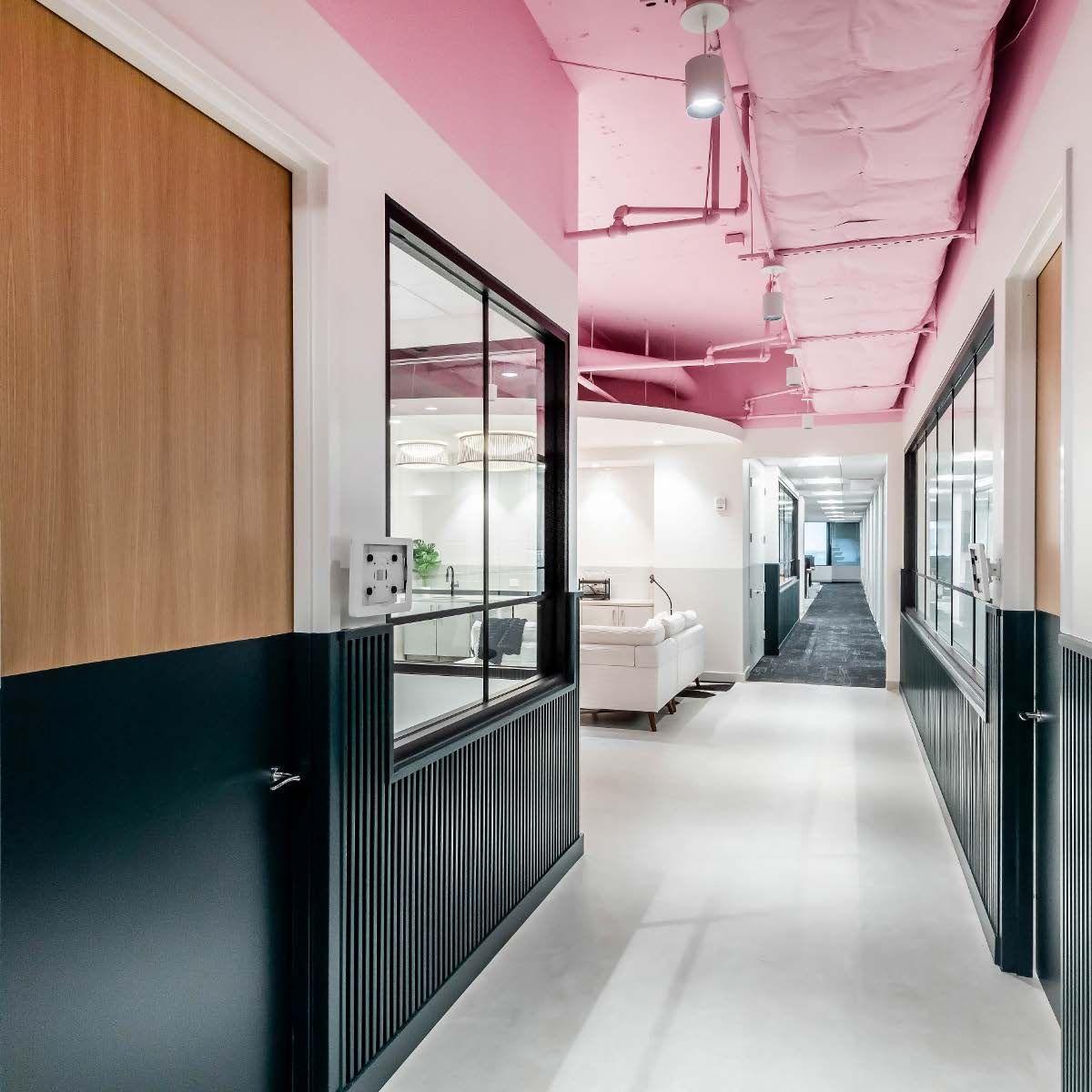Hallway with pink ceiling, black and wood-paneled walls, and white floor.