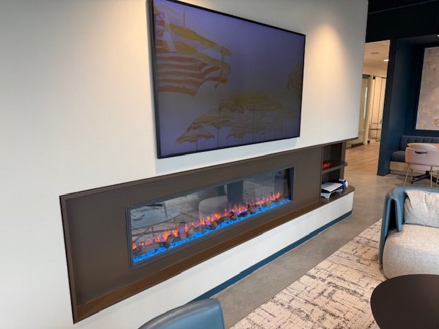 Fireplace with blue flames under a mounted TV on a white wall.