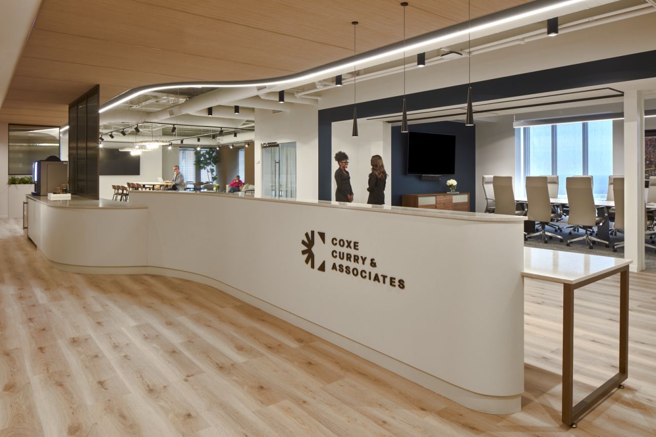 Reception area with white curved desk, logo, two people, conference room, and modern interior design.