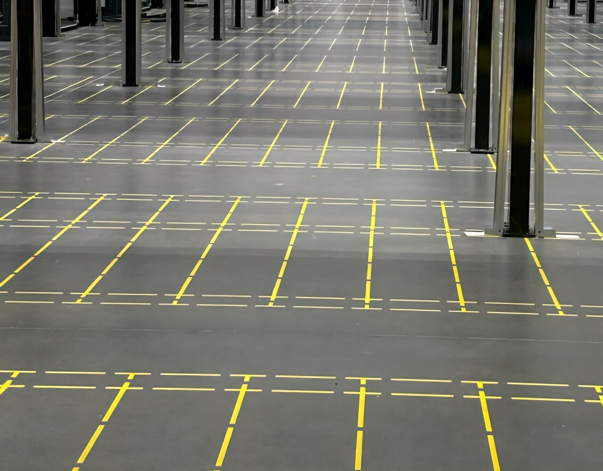 Gray warehouse floor with yellow grid lines and metal support columns.