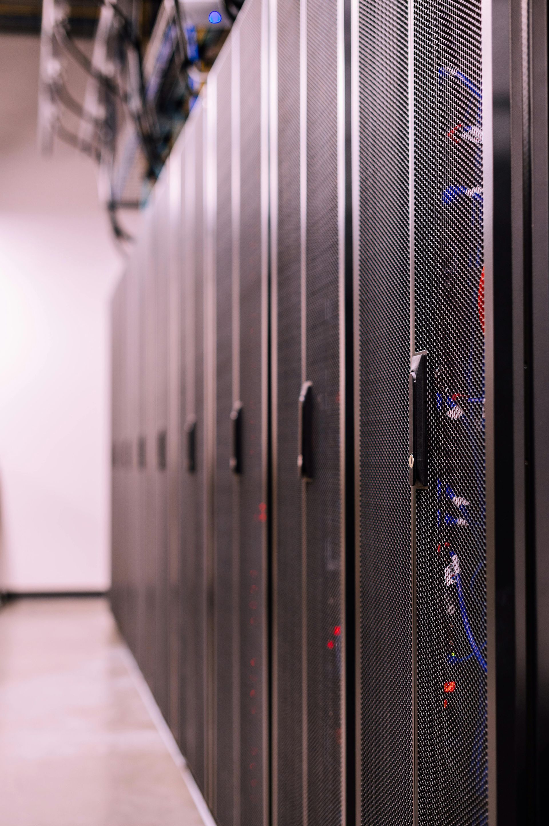 Row of black server racks in a data center, lit from above, focus on the front rack.