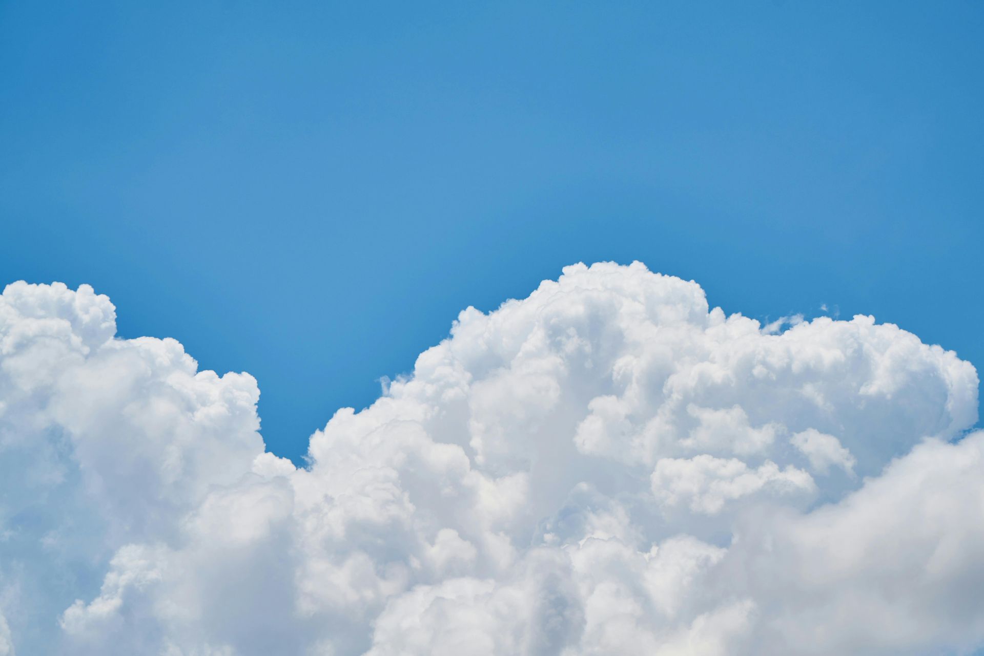Bright blue sky with puffy, white cumulus clouds.