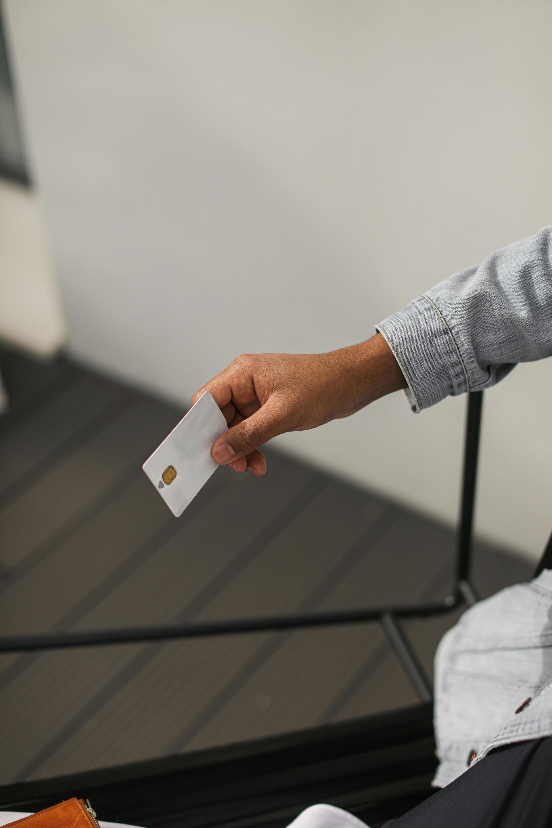 Person's hand holding a white card with a gold chip. The person is in a room, arm extended.