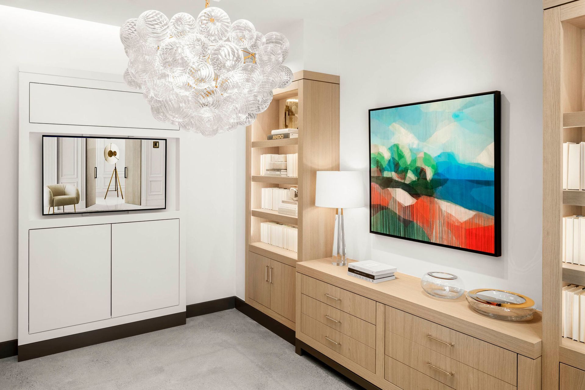 Elegant home office with built-in bookshelves, a large abstract painting, and a decorative bubble chandelier.
